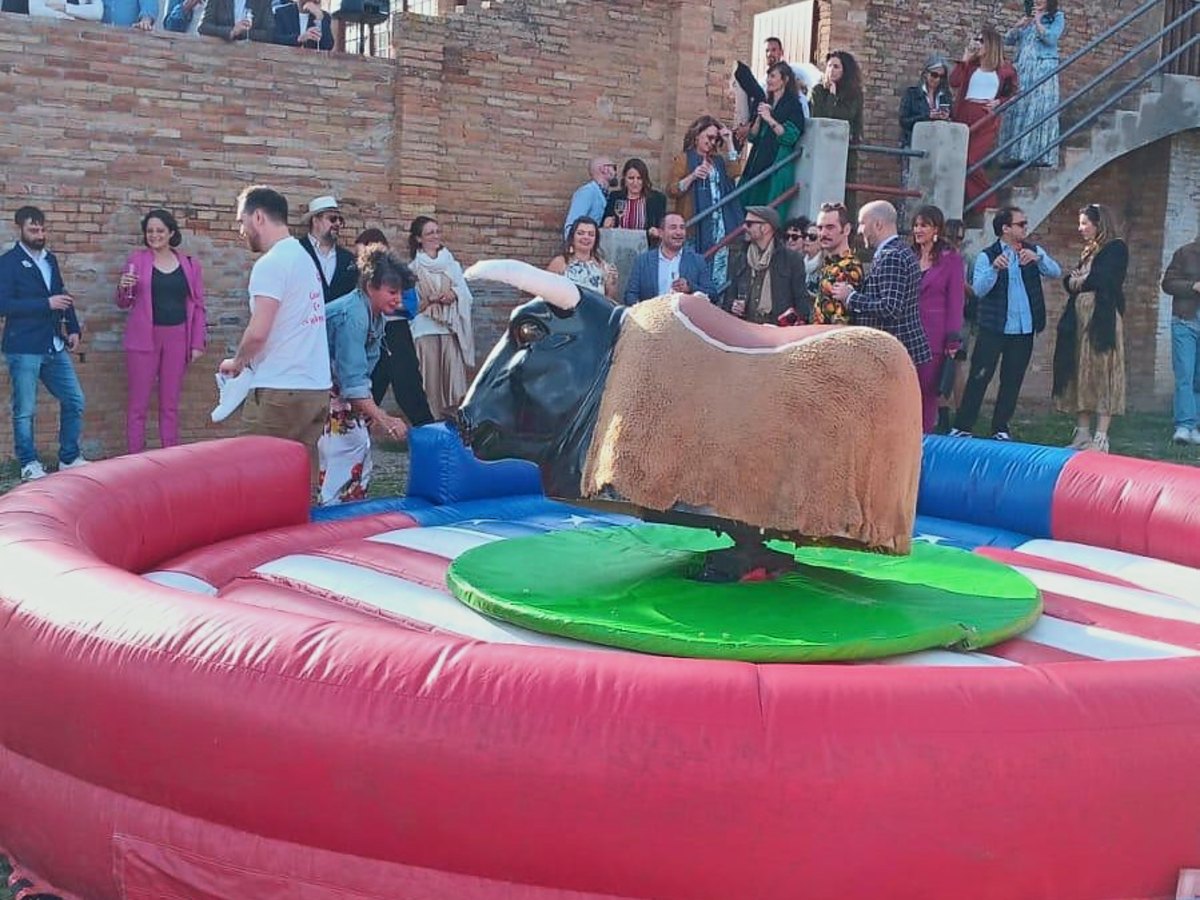 Toro mecánico sobre la colchoneta americana con los invitados de un evento alrededor
