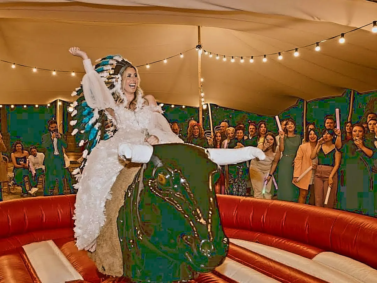 Novia montando el toro mecánico en una boda mientras los invitados animan