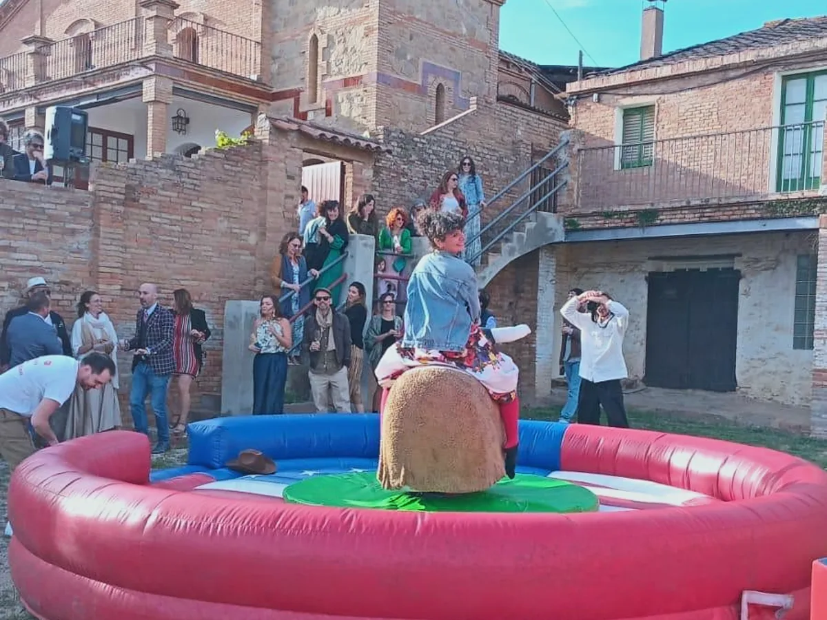 Invitado montando el toro mecánico con los asistentes alrededor