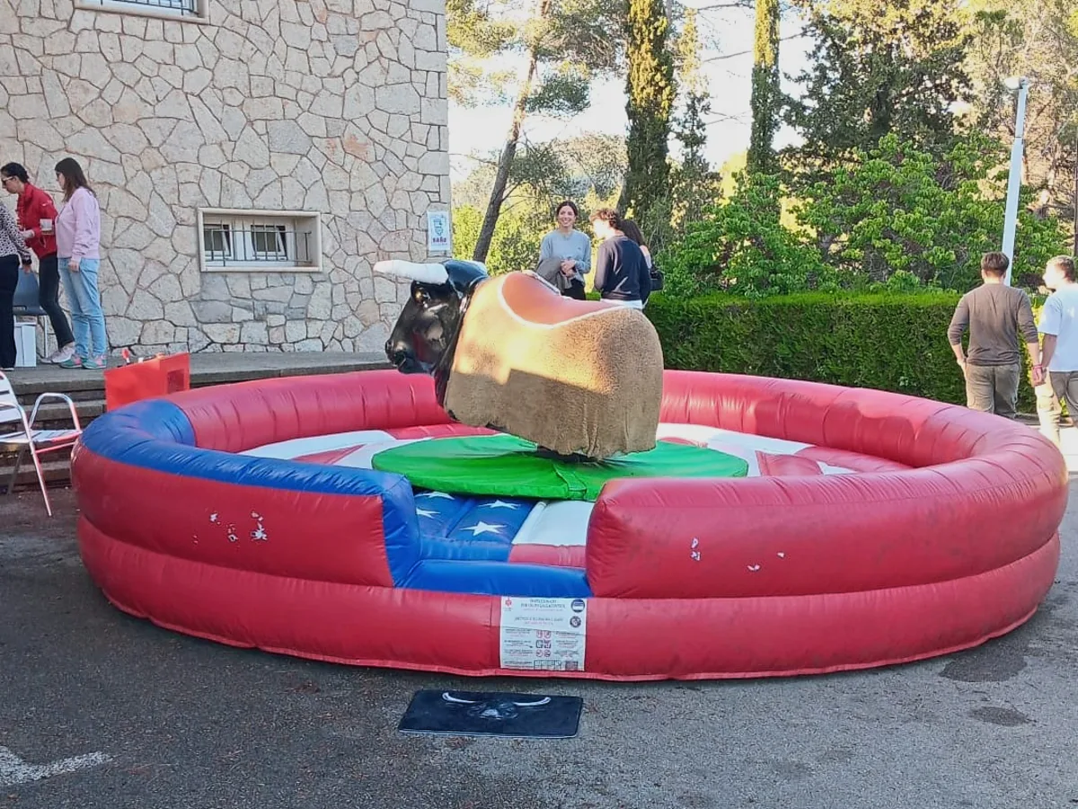 Toro mecánico montado en el exterior de una masía con los invitados al fondo