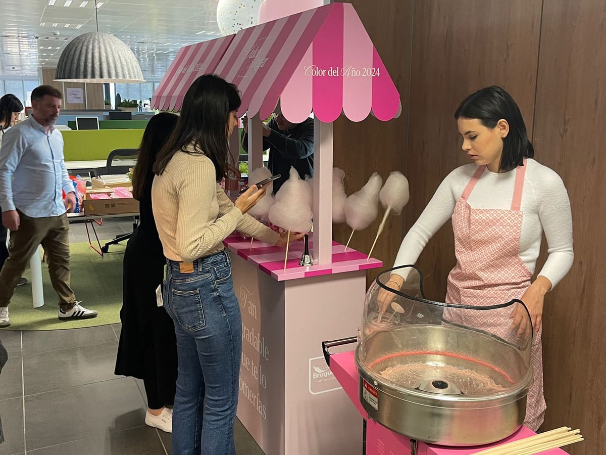Chica preparando algodón de azúcar en un puesto rosa en un evento de empresa
