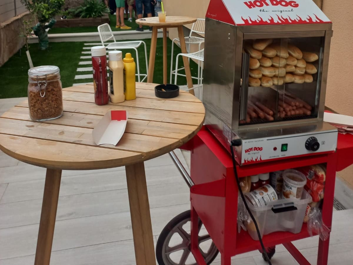 Carrito de hotdogs con salsas en un jardín