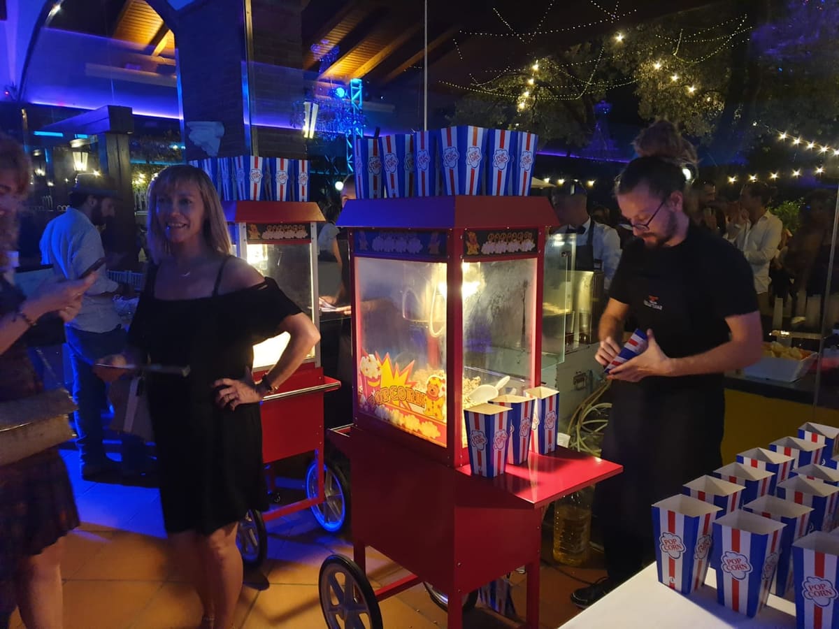 Carrito de palomitas rojo sirviendo en una fiesta nocturna con luces