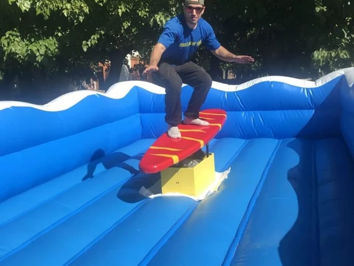 Chico en equilibrio sobre la tabla del surf mecánico al aire libre